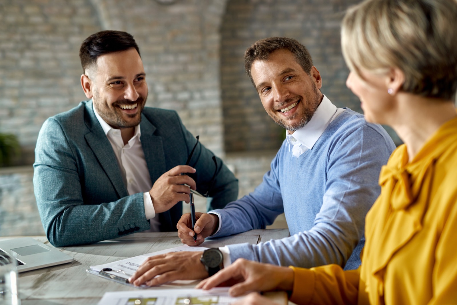 A mortgage broker sharing a laugh with two clients across a table