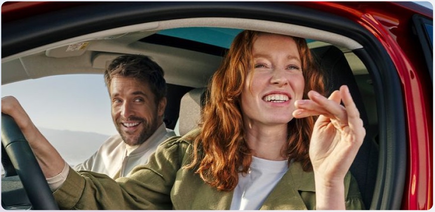 A couple smiling in their car on a coastal drive